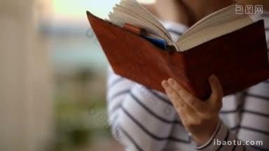 倾斜的镜头，一个女人<strong>正在</strong>沉思或梦想，而风搅动着书的书页